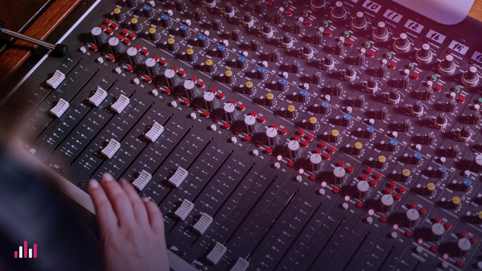 A hand on the faders of an analogue mixing console
